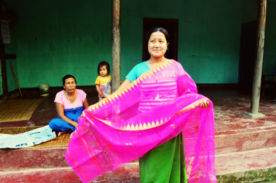 A weaver displays a finished shawl